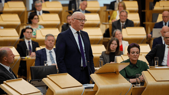 First Minister John Swinney MSP speaking in the Debating Chamber