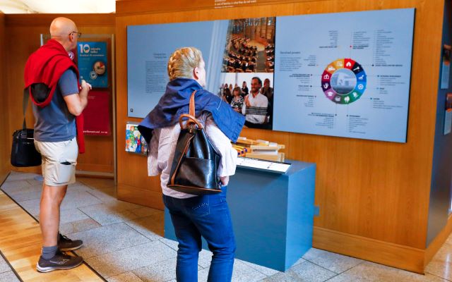 visitors look at a panel of information in an exhibition