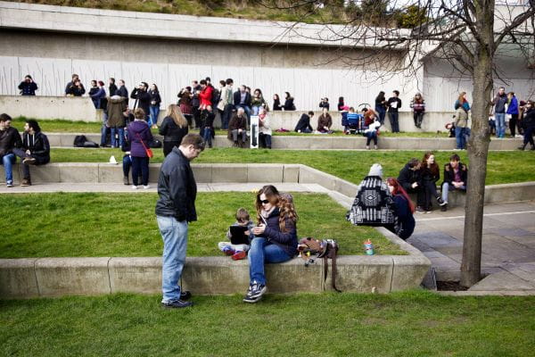 people sit in the landscaped garden area outside the parliament