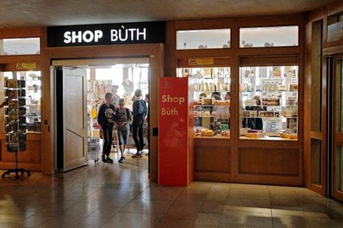 the entrance to the parliament gift shop, with a sign above saying 'shop' in english and 'buth' in gaelic