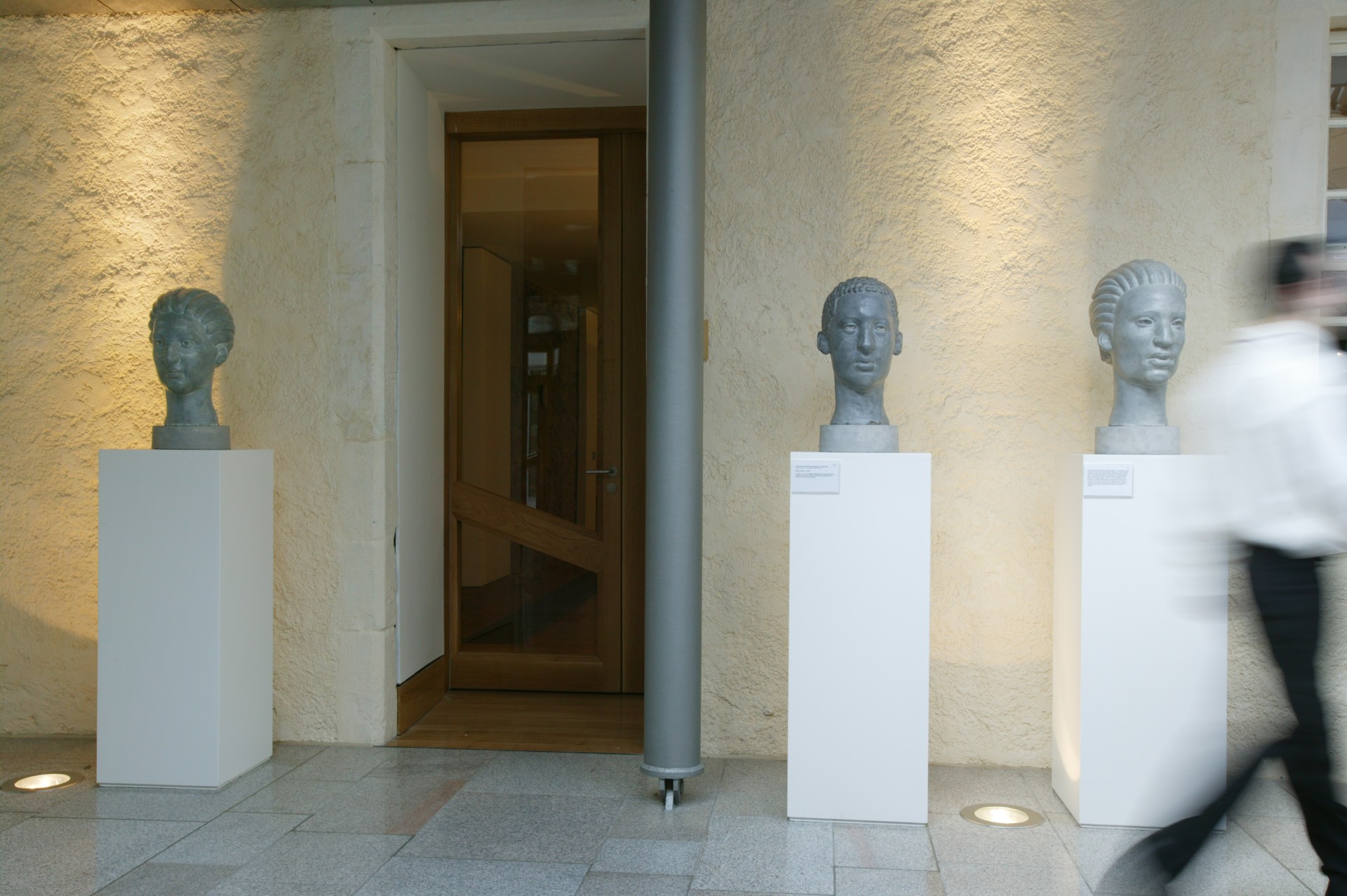 Three busts of human heads made of concrete. 