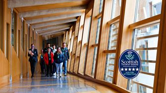 A group of visitors are led up the glass corridor by a tour guide