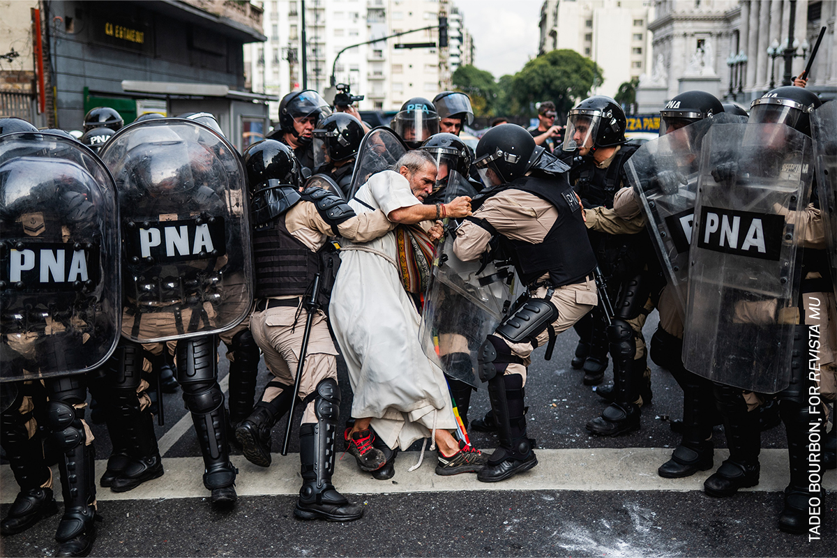 Police detain Father Jorge “Chueco” Romero during a pensioners’ protest in Buenos Aires, Argentina. Members of the “Opción por los Pobres” (Option for the Poor) clergy have joined weekly demonstrations against pension freezes and cuts to essential medical coverage. While Romero was thrown to the ground, he was later released.