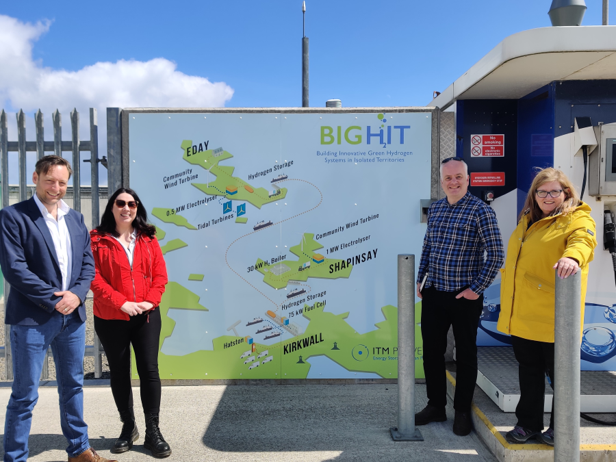 A group of MSPs pose for a photograph in front of a large-scale map of the Orkney archipelago.